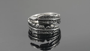 Macro detail of vintage oxidized feather ring with realistic silver texture on mirror surface