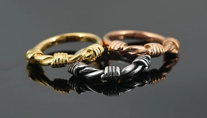 Macro shot of three twisted rope design rings in gold, rose gold and silver finish
