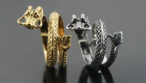 Close-up of golden and silver dragon wrap rings showing detailed scales and dragon head design