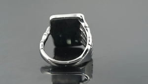 Macro side view of vintage men's steel ring with black gemstone and bone texture