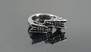 Close-up of vintage dragon ring featuring detailed scales and twin heads in retro steel