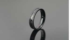 Macro view of matte black titanium ring with frosted finish and single zircon inlay