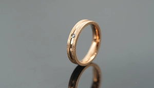 Macro detail of rose gold matte titanium ring with sandblasted finish and small diamond