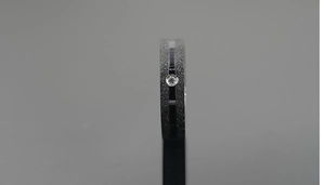Detail of black matte titanium ring with a centered polished groove and single clear zircon