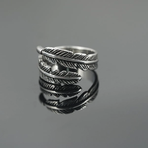 Vintage oxidized titanium steel feather ring with detailed carving on black reflective surface