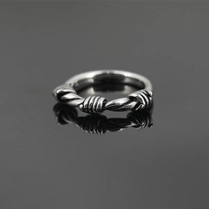 Retro titanium steel braided knot ring with vintage oxidized finish on grey mirror surface