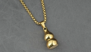 Polished golden stainless steel gourd pendant on a box chain macro detail shot