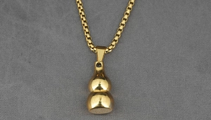 Macro shot of gold stainless steel gourd pendant on a square box chain for men