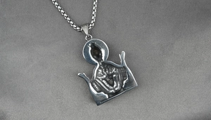 Detail shot of a silver titanium steel Virgin Mary pendant necklace on grey satin background