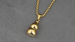 Detailed close-up of golden hulu pendant necklace with polished mirror finish and box chain