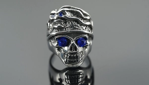 Macro shot of gothic steel skull ring featuring blue gemstone eyes and vintage finish