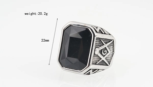 Macro detail of men's Masonic steel ring with black gemstone and engraved square symbol