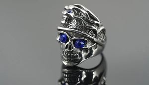 Macro detail of gothic skull ring in vintage steel finish with deep blue crystal eyes