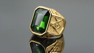 Macro view of gold Freemason ring featuring a large rectangular emerald-cut green gemstone