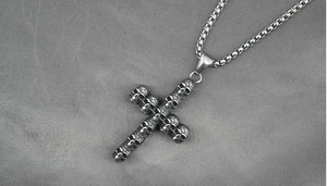 Détail macro du pendentif croix tête de mort en acier titane oxydé avec chaîne box