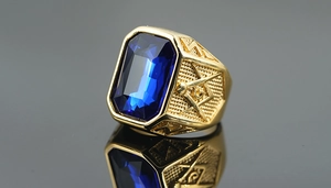 Macro detail of men's gold titanium ring with blue sapphire and Masonic symbols