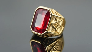 Macro detail of men's gold Masonic ring with red rectangular gemstone and compass emblem