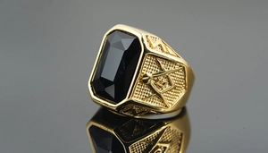Macro shot of gold Masonic ring featuring a faceted black stone and detailed side engraving