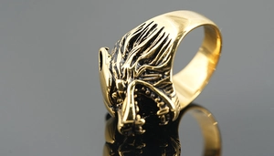 Macro shot of vintage golden wolf head ring with detailed antique finish on dark background