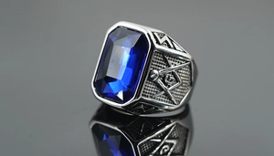Macro shot of silver Freemason ring with a large blue gemstone and G symbol
