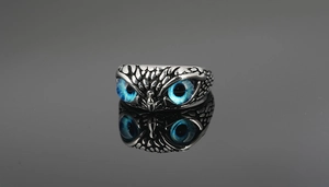 Detalle de anillo de búho retro con ojos azules y plumas plateadas talladas