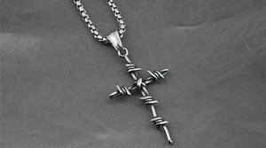 Macro view of a retro barbed wire cross pendant on a sturdy box chain necklace