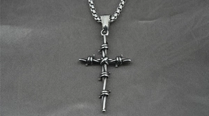 Macro view of a silver titanium steel cross pendant with detailed wire-wrapped design