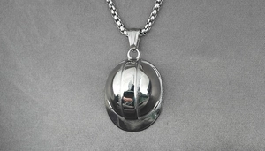 Macro shot of polished stainless steel construction helmet pendant on box chain