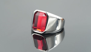 Macro detail of men's silver ring with large emerald-cut red gemstone and polished finish