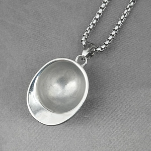 Vintage stainless steel necklace with silver safety helmet pendant on grey fabric