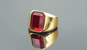 Macro side view of rectangular faceted red gemstone set on a wide gold ring base