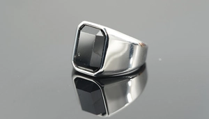 Macro shot of polished silver ring featuring a large rectangular black gemstone inlay