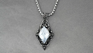 Macro view of vintage silver rhombus pendant with clear zircon and gothic patterns