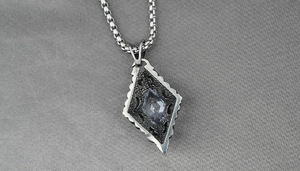 Detailed macro view of rhombic gothic pendant with blue-grey gem and box chain