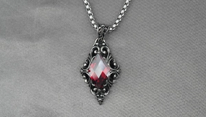 Macro shot of gothic pendant with red diamond-cut gemstone and vintage silver engraving