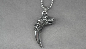 Détail du pendentif tête de loup et dent courbée sur une chaîne en acier