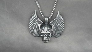 Détail d'un collier gothique avec crâne, ailes de plumes et finition en argent vieilli