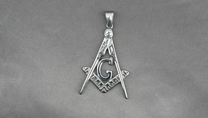 Macro detail of silver Freemason pendant with compass, square symbol and G letter