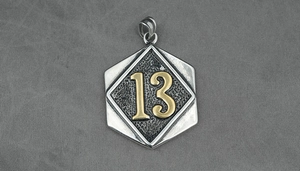 Macro shot of silver hexagonal pendant with a golden number 13 and hammered texture
