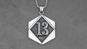 Close-up of silver hexagon pendant with number 13 and honeycomb texture on box chain