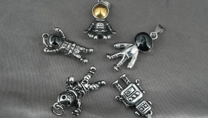 Detailed close-up of retro astronaut and robot pendants in vintage silver finish
