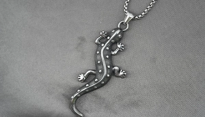 Detailed macro view of retro gecko pendant with embossed dot textures and box chain