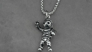 Detailed close-up of a vintage silver astronaut pendant with a square pearl chain necklace