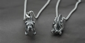 Vue détaillée de deux pendentifs en acier titane motif bouledogue et bête sur chaînes