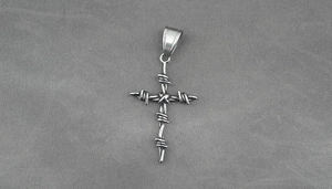 Dettaglio di un ciondolo a croce di spine gotico argento su tessuto twill grigio