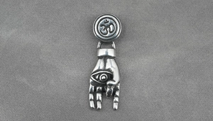 Macro detail of vintage stainless steel palm pendant with Om symbol and evil eye design