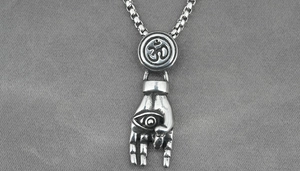 Macro detail of vintage silver Om pendant with Hamsa eye symbol on a box chain
