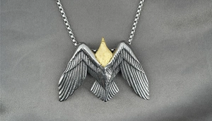 Macro d'un pendentif aigle bicolore avec plumes en argent et tête dorée détaillée