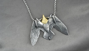 Détail d'un pendentif aigle vintage bicolore argent et or avec une chaîne à mailles