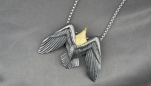 Gros plan détaillé du pendentif aigle bicolore avec plumes gravées et chaîne à mailles